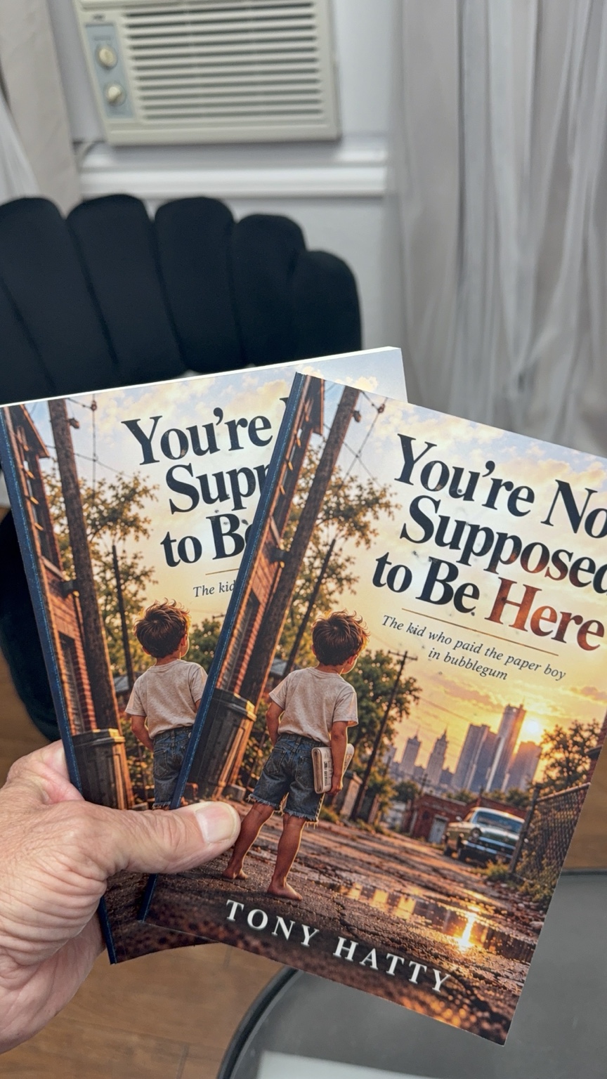 Tony Hatty holding two copies of his memoir You’re Not Supposed to Be Here